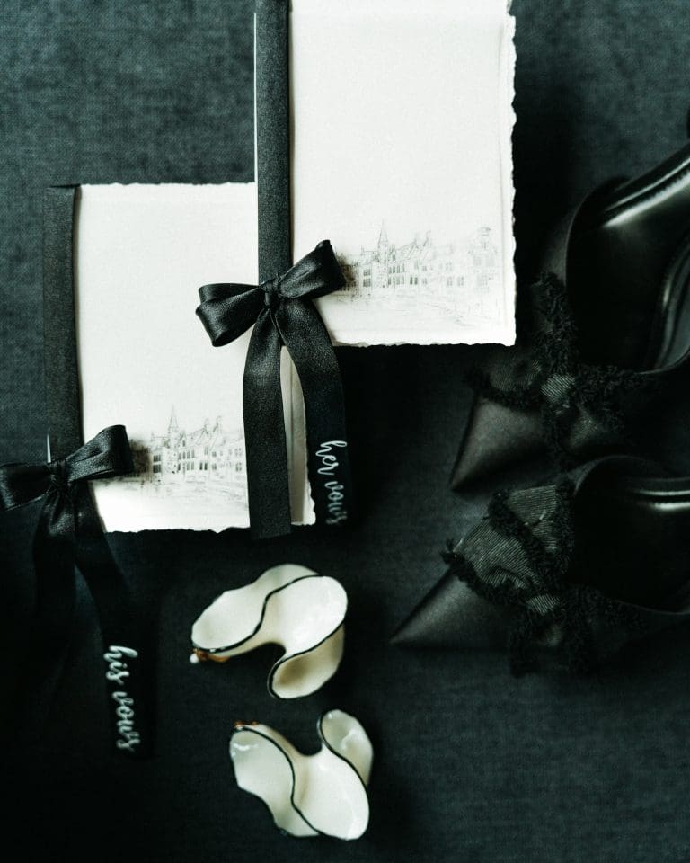 Accesorii elegante de nuntă în alb și negru: caiete de jurăminte, pantofi și elemente ceramice, fotografiate în lumină soft