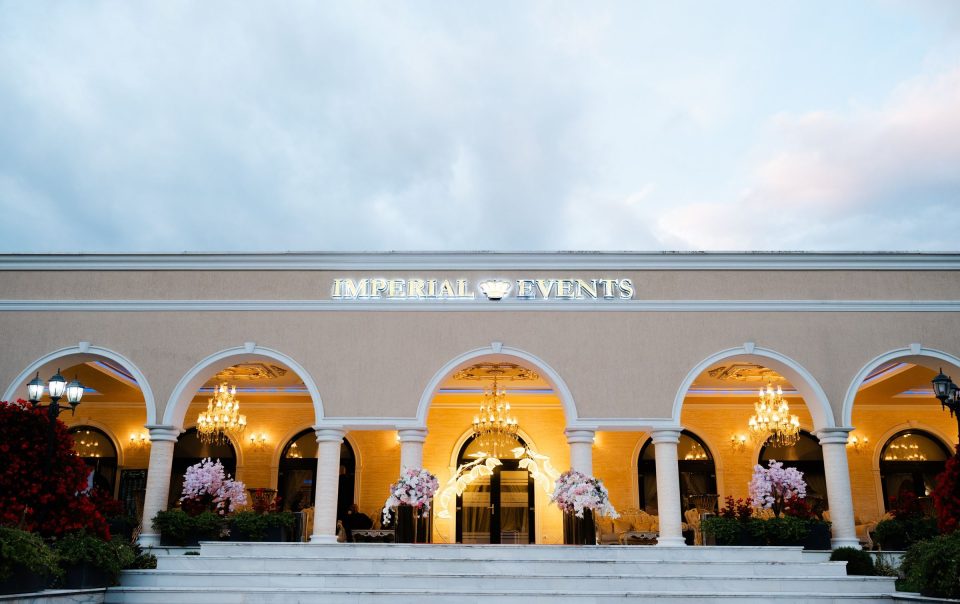 Fațada Imperial Events Deva, cu arcade albe luminate de candelabre, la căderea serii