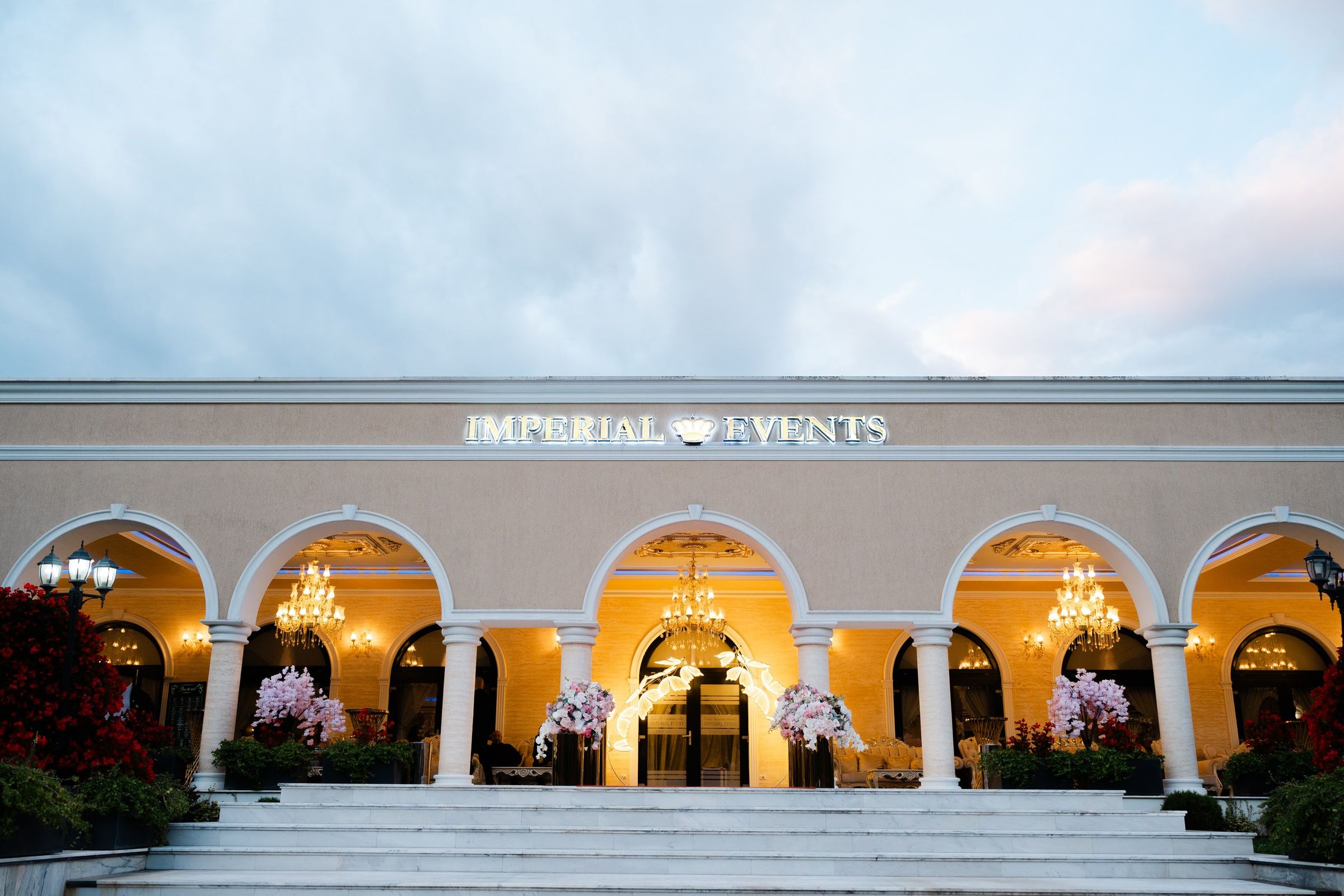Fațada Imperial Events Deva, cu arcade albe luminate de candelabre, la căderea serii