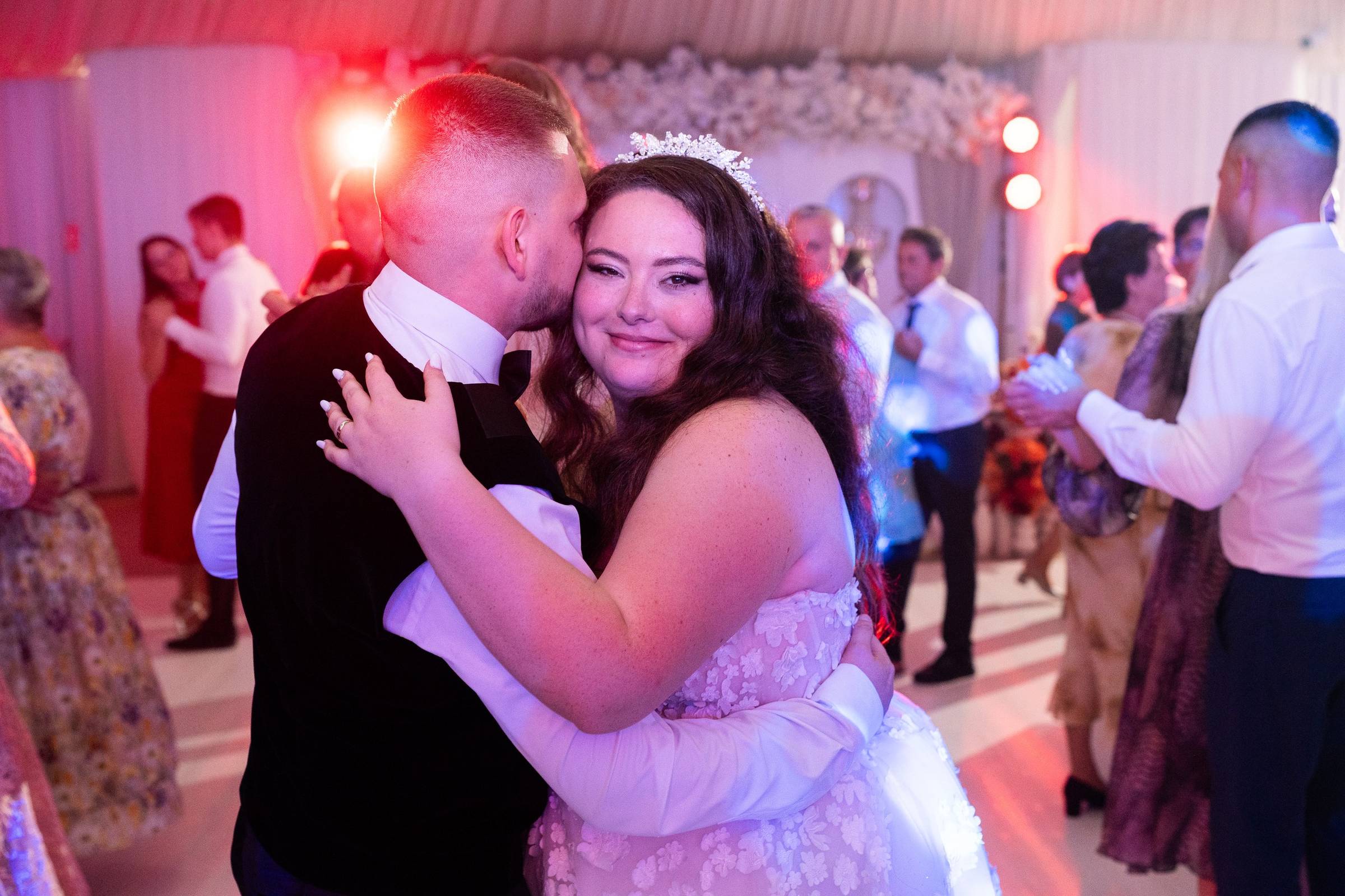 Mirii dansează îmbrățișați pe ringul de dans, în mijlocul petrecerii de nuntă